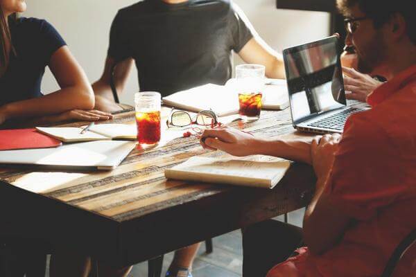 Four coworkers with good posture talking at a small table with drinks