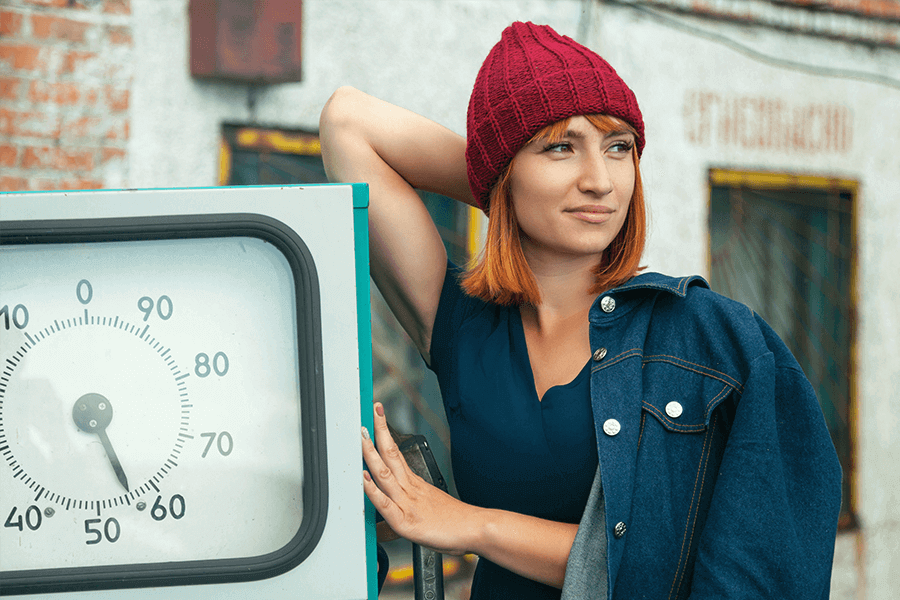 Confident woman leaning against a meter looking into the distance