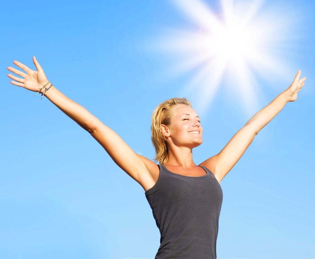 Woman smiling and spreading her arms open in the sunlight