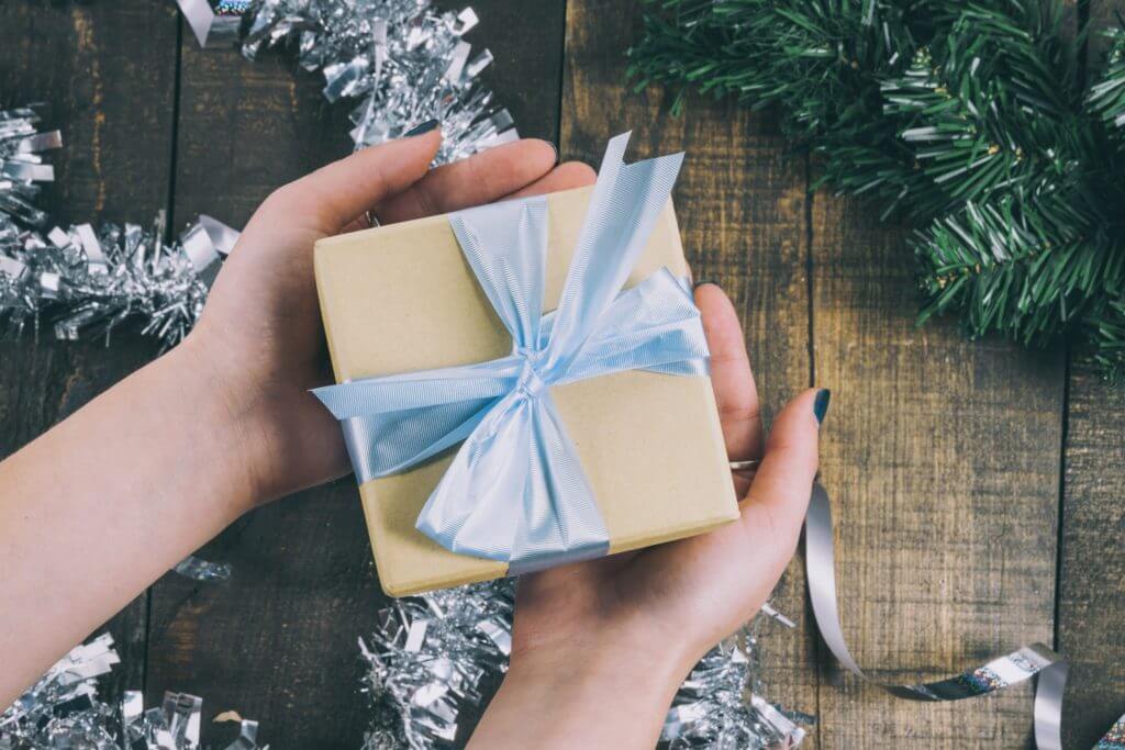 Woman holding a wrapped present over holiday decorations