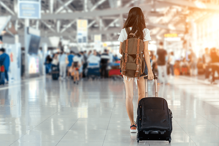 Woman walking through an airport with a luggage bag