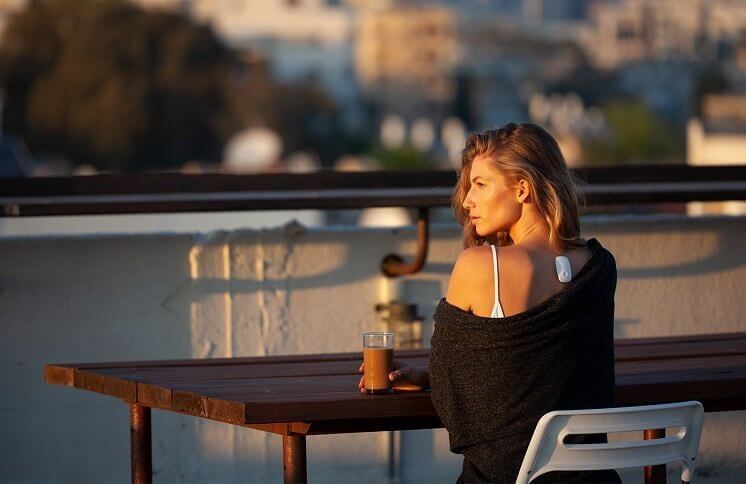 Woman sitting outside looking at the sunset with her Upright device on her upper back