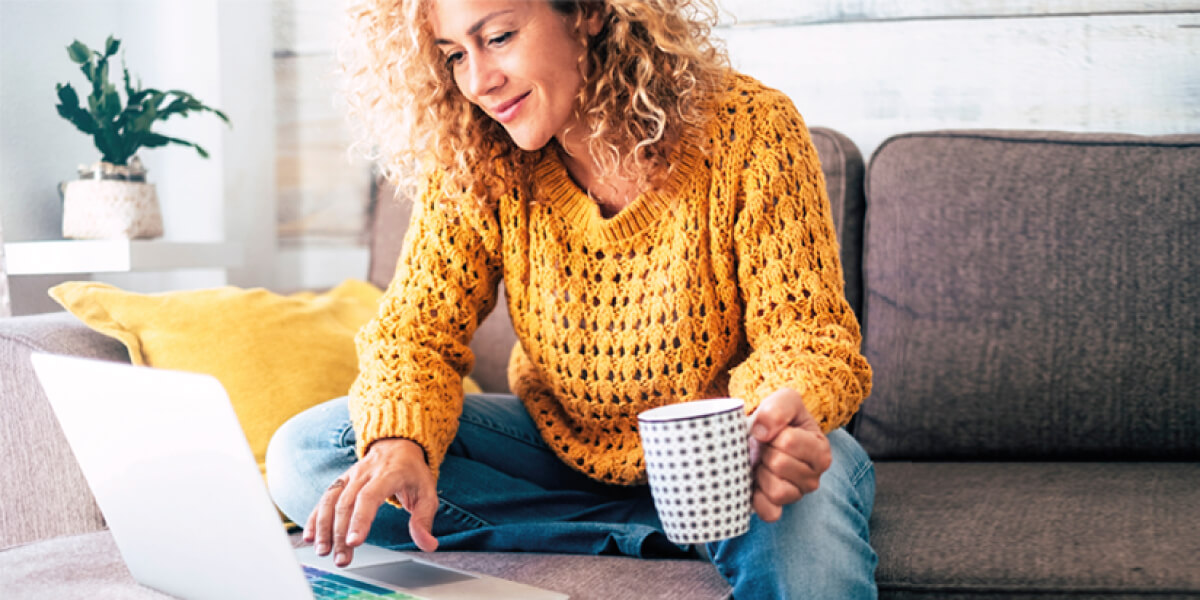 Woman in yellow sweater hunching over her laptop