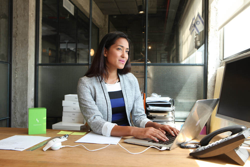 Smiling woman with good posture working at her laptop in an office