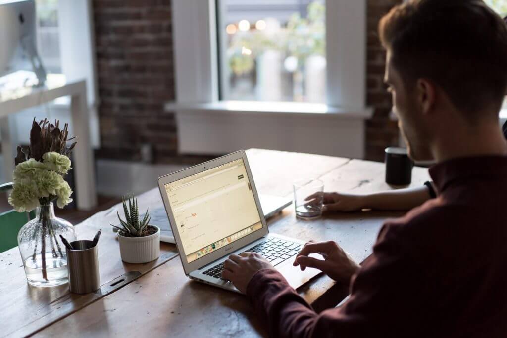 Man looking at the benefits of good posture on his laptop