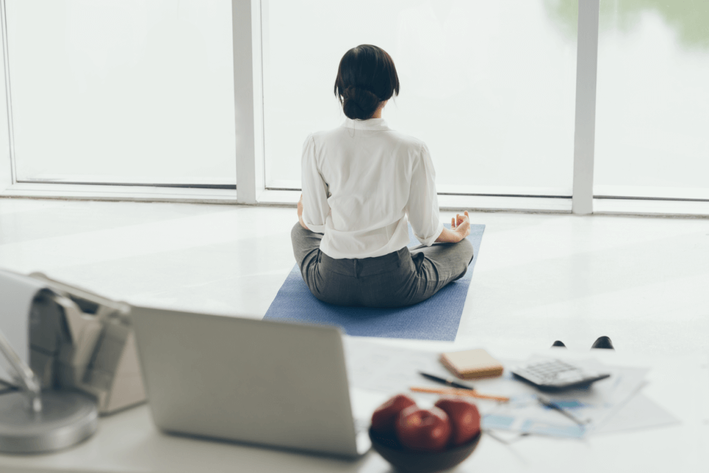 Woman taking a break from work and meditating by a large window