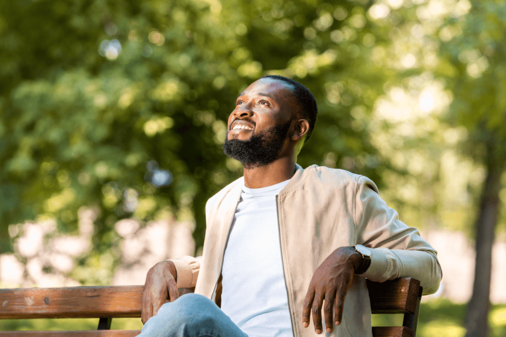 Men sitting on a park bench smiling toward the sky