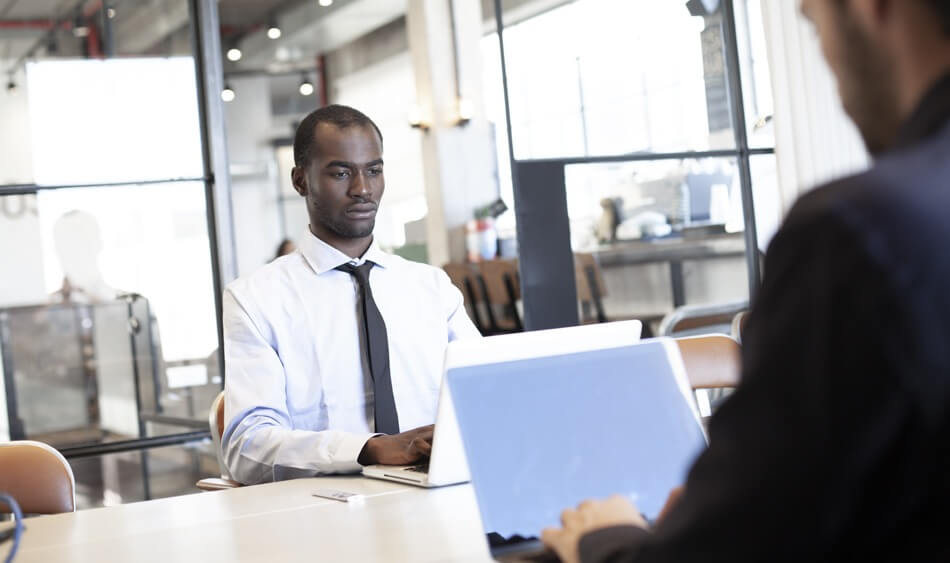 Man working in an office on his laptop with good posture