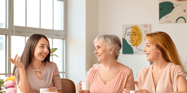 Three women holding mugs and smiling together