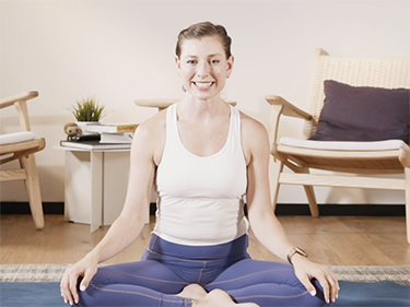 Upright fitness coach smiling on a yoga mat