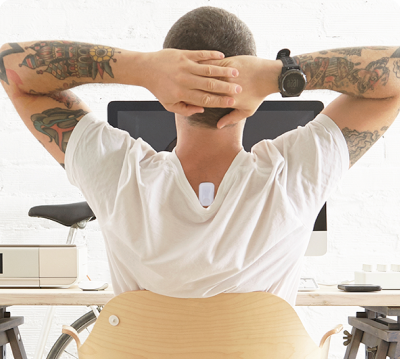Man with tattoos relaxing at his desk with the Upright Go on his upper back