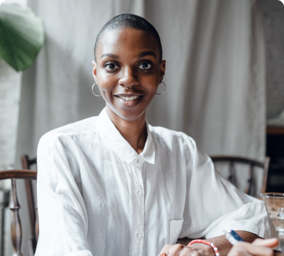 Woman sitting in a chair smiling while holding a pen